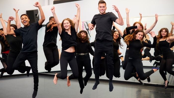 Performers in black clothes jump in air