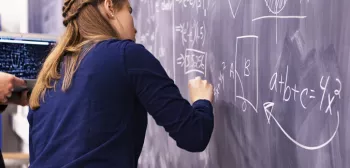 Student draws a formula on chalk board