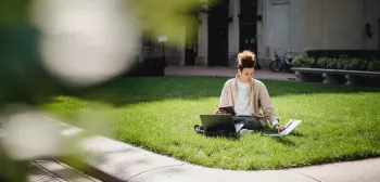 Focused ethnic man studying on lawn in university campus