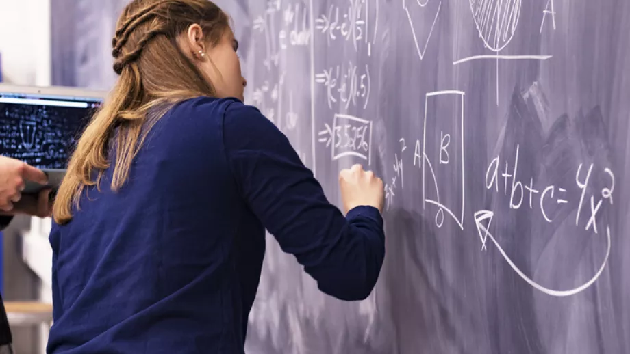 Student draws a formula on a chalk board